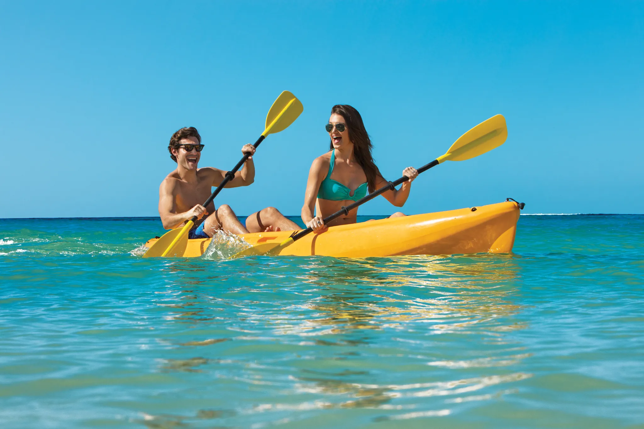 Couple kayaking together in crystal-clear Caribbean waters at Dreams Dominicus La Romana Resort.
