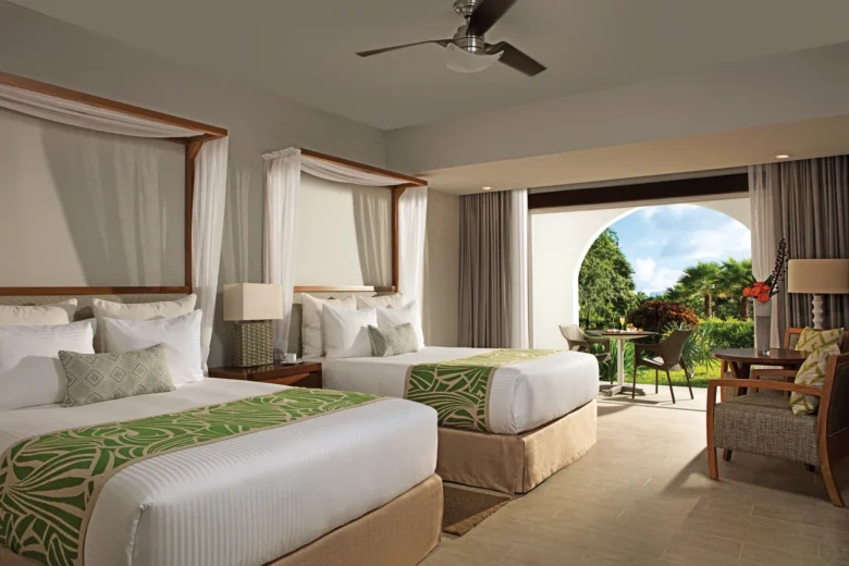 Deluxe room with two double beds and furnished terrace at Dreams Dominicus La Romana overlooking the resort gardens.